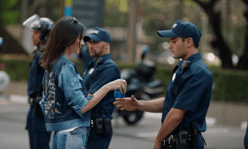 كيندال جينر تقدم زجاجة بيبسي إلى ضابط شرطة في اعلان بيبسي